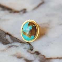 Dive into elegance with the Blue Lagoon Statement Ring. Featuring a large, mesmerizing turquoise stone at its center, this ring is set into 18K gold-plated brass, radiating a warm and luxurious glow thanks to a hammered texture. Designed with your comfort in mind, it is hypoallergenic and nickel-free, ensuring it's as gentle on your skin as it is captivating to the eye. Elevate any outfit with the Blue Lagoon Statement Ring and let its timeless beauty make a bold statement. DETAILS ONE SIZE, ADJ The Blue Lagoon, Squash Blossom Necklace, Turquoise Rings, Kingman Turquoise, Blue Lagoon, Brass Material, Turquoise Stone, Statement Ring, Timeless Beauty