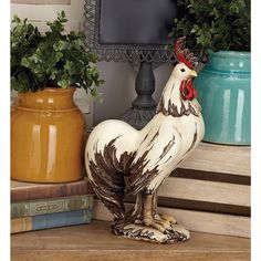 a rooster figurine sitting on top of a table next to some potted plants