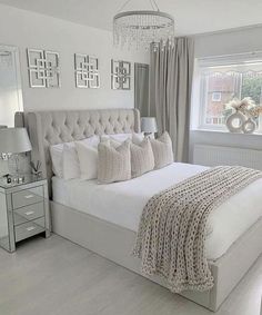 a bedroom with a large bed and chandelier hanging from the ceiling