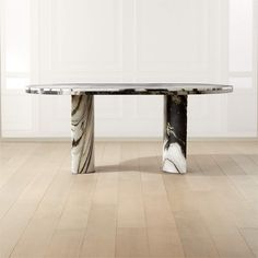 a marble dining table with black and white designs on the top, in an empty room