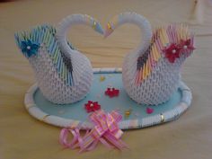 two white swans made out of yarn sitting on top of a blue tray with pink bows