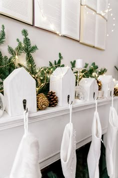 christmas stockings hanging from a mantel with pine cones and ornaments on them in front of an open book