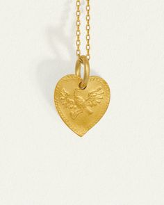 Graced with eagle reliefs on both sides, this solid gold heart necklace embodies bravery and love. The design draws inspiration from the Latin word for heart, originally signifying the courageous expression of one's true feelings.  
 Crafted from 24k solid gold, this double-sided pendant exudes a rich, tactile lustre that enhances its allure. A 14k yellow gold curb chain completes the Courage Necklace. Symbolic Engraved Heart Pendant Necklaces, Symbolic Yellow Gold Heart Pendant Necklace, Symbolic Engraved Heart Pendant Necklace, Symbolic Heart Pendant Necklace Engraved, Symbolic Gold Heart-shaped Necklaces, Heart-shaped Coin Pendant Necklace As Gift, Heart Shaped Coin Pendant Necklace, Heart Shaped Coin Pendant Necklace Gift, Symbolic Yellow Gold Heart Pendant Jewelry