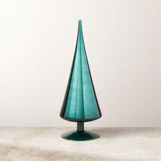 a green glass vase sitting on top of a table next to a white wall and floor