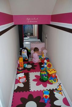 a small child's room with toys on the floor and pink carpeted walls