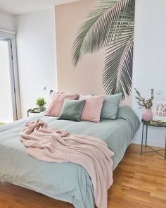 a bedroom with a palm tree painted on the wall and bedding in pastel colors