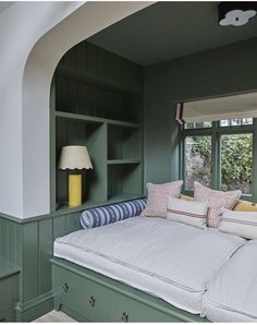 a room with green walls and white bedding, pillows on top of the headboard