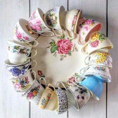 an arrangement of teacups arranged in a circle on a white wooden table top