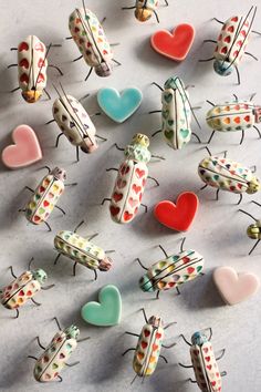 many different colored bugs and hearts on a white surface with one bug facing the camera