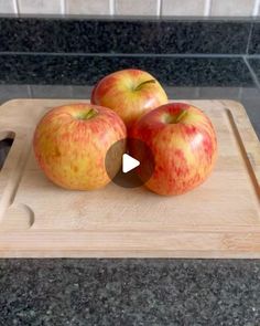 three apples sitting on top of a cutting board