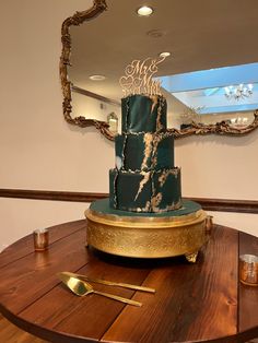 a green and gold cake sitting on top of a wooden table next to a mirror