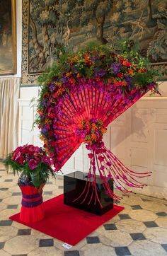 a red and purple flower arrangement in a vase on top of a checkered floor