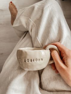 a person laying on top of a bed next to a white cup with the word tronjo written on it