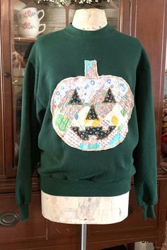 a green sweater with a jack o lantern on it