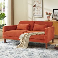 a living room with an orange couch and rug