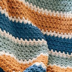 a crocheted blanket is laying on top of a chair with a blue, yellow and white afghan