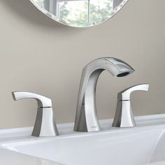 a bathroom sink with two faucets and a round mirror