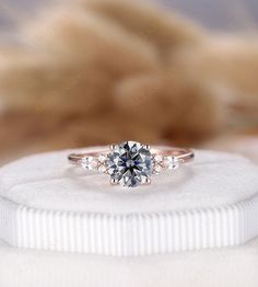 an engagement ring on top of a white cloth with a furnishe in the background