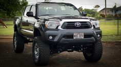 a gray toyota truck parked in front of a fenced off area with an animal behind it