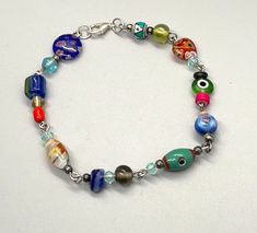 This fun multicolored ankle bracelet will get you noticed with its whimsical beads in bright colors and artsy design. Wear it year-round with everything from casual to more sophisticated styles. Inspired by the season, this handmade wire linked anklet will put a smile on your face every time you put it on. It is adjustable with a lobster claw closure for a secure and custom fit. Approx 9 inches + .5 inch extension  #handmadebeadedanklet #colorfulglassbeads #cheapbeadedanklebracelet #doubleddezin Colorful Summer Jewelry, Artsy Design, Beaded Ankle, Beaded Anklet, Ankle Bracelet, Handmade Wire, Anklet Jewelry, Body Jewellery, Bracelet Handmade