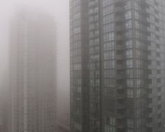 two tall buildings in the fog on a cloudy day