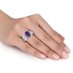 Add a dash of royalty to your attire with this stunning Amethyst and Created White Sapphire Halo Wide Band Ring. Crafted in glittering sterling silver, it features an oval-cut, prong-set amethyst gemstone (10 x 8mm) at the center with a halo of 30 round-cut, prong and pave-set created white sapphire gemstones studded on both the sides of the wide band. This broad band with a sparkling gemstone line creates an unique and shining piece, which draws immediate attention. Buffed with luster, this gor Elegant Sterling Silver Amethyst Birthstone Ring, Classic Silver Amethyst Ring With Gemstone Accents, Elegant Sterling Silver Amethyst Ring With Accent Stones, Fine Jewelry Amethyst Ring With Accent Stones, Elegant Lavender Jewelry With Center Stone, Fine Jewelry White Gold Amethyst Ring With Gemstone Accents, Oval Amethyst Ring With Cubic Zirconia And Gemstone Accents, Oval Amethyst Ring With Cubic Zirconia Accents, Elegant Cubic Zirconia Amethyst Ring