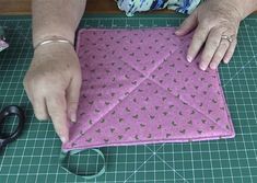 an older woman is cutting fabric on a table with scissors and other items around her