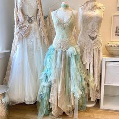 three mannequins with dresses on display in a shop window, one is white and the other is blue