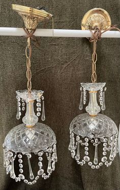 two crystal chandeliers hanging from a curtain rod