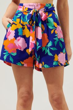 Spend the day basking in the sun, wearing these fitting shorts. Fun colored floral motifs against a blue-ground decorate these breezy shorts that sit high on the hips. A belt is added for a refined feminine look, while the shorts start to widen. They maintain a relaxed fit throughout the hips and thighs.- Hook and clasp- Zipper fly- Pockets- Bubble crepe- Color: Cobalt Pink OrangeSize + Fit - Model is 5'8" and wearing size XS- Measurements taken from size S - Waist: 13"- Inseam: 3" Fabric Self:9 Blue Tropical Print Beachwear Shorts, Spring Vacation Shorts, Blue Tropical Print Shorts, Multicolor Floral Print Bottoms For Summer, Spring Vacation High-waisted Shorts, Spring Beachwear Shorts For Day Out, Spring Bermuda Beachwear Bottoms, Multicolor Floral Print Summer Bottoms, Poolside Tropical Print Shorts