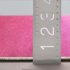 a ruler is on the floor next to a pink rug