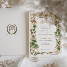 the wedding card is surrounded by flowers and greenery, with an ornate design on it