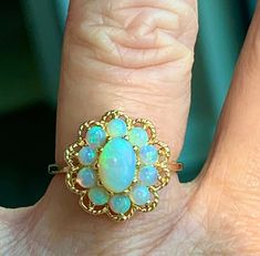 "Opal ring, vintage Australian opal engagement ring in 14k yellow gold. Beautiful center opal stone with wonderful blue and green color hues. Center stone measures 7mm x 5mm (about .55 carat). Ten accompanying stones measure ~2.8mm each and are superbly matched with the main opal, estimated .08 carat each. Total opal carat weight for the ring is estimated 1.19 carats. Excellent condition! Ring weighs 3.4 grams. Size 6 and can be sized +- 3.5 sizes by adding sizing to your order for 45- here: htt Classic Luxury Yellow Gold Opal Ring, Opal And Turquoise Ring, Luxury Cabochon Opal Ring For Engagement, Vintage Opal Ring As A Gift, Heirloom Yellow Gold Opal Ring With Gemstone, Heirloom Style Round Opal Ring, Heirloom Opal Ring, Vintage Opal Rings In Yellow Gold, Anniversary Yellow Gold Opal Cabochon Ring