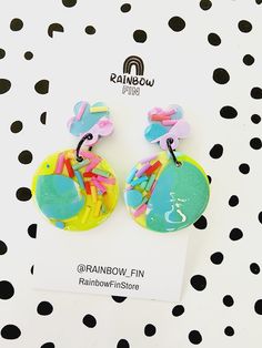 pair of colorful earrings on white polka dot paper with black and white dots in the background