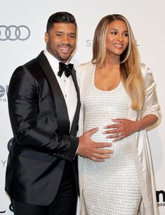 a man and woman standing next to each other in front of an audi event sign