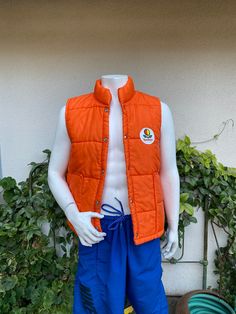 "Vintage nylon quilted puffer vest by Swingster World of Wearables.  Bright orange with Sunkist applique.  Snaps up the front.  Big patch pockets.  Excellent vintage condition with a couple of minor spots (see last 2 pictures). label:  Swingster World of Wearables fabric:  quilted nylon and dacron hollofil size:  labeled size is large.  Modern size of men's small-medium is just an estimate.  Please check measurements for an accurate fit.  Questions are welcome! vest was measured across the front side lying flat underarm to underarm 23\" length 24 1/2\"  shoulder 16\"" Cotton Puffer Vest, Orange Sleeveless Winter Vest, Winter Orange Sleeveless Vest, Casual Orange Cotton Vest, Vest Puffer, Puff Vest, Quilted Puffer Vest, Vest Outfits, Puffer Vest