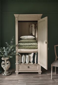 an armoire with clothes and pillows in it