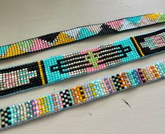 three beaded bracelets sitting on top of a white table next to each other