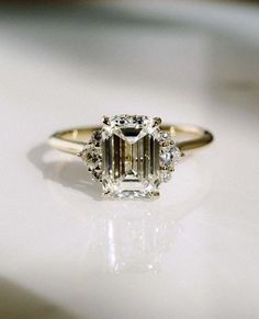 an emerald cut diamond ring on a white surface