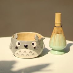 a ceramic animal cup next to a bottle on a table