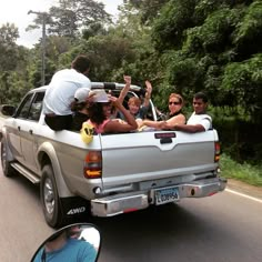 a group of people riding in the back of a pick up truck on a road