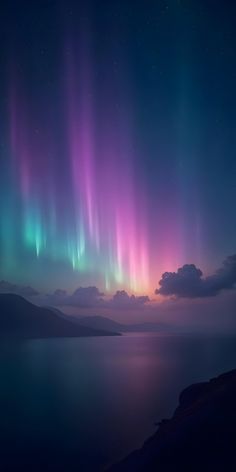 the aurora lights shine brightly in the night sky over an ocean and mountain range as seen from across the bay