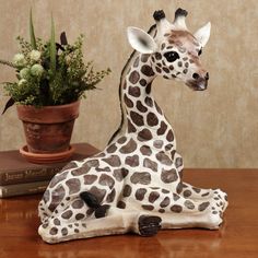 a ceramic giraffe sitting next to a potted plant