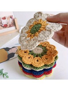 a stack of crocheted coasters sitting on top of a table next to a book