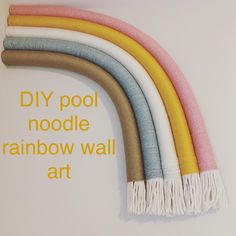 a rainbow colored wall hanging on the side of a white wall with text over it that reads diy pool noodle rainbow wall art