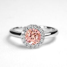 a ring with an oval shaped pink diamond in the center and white diamonds around it