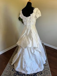 a white wedding dress is on display in a room with wood floors and a rug