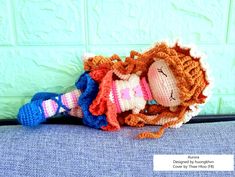 a crocheted doll laying on top of a blue couch next to a green wall