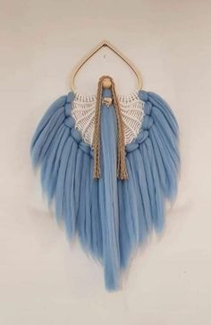 a blue and white angel wing hanging on a wall with a tasseled handle