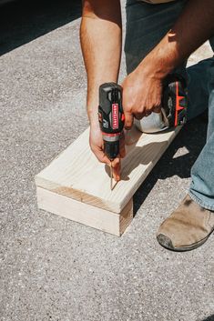 a man using two drillers on a piece of wood with another person's hand